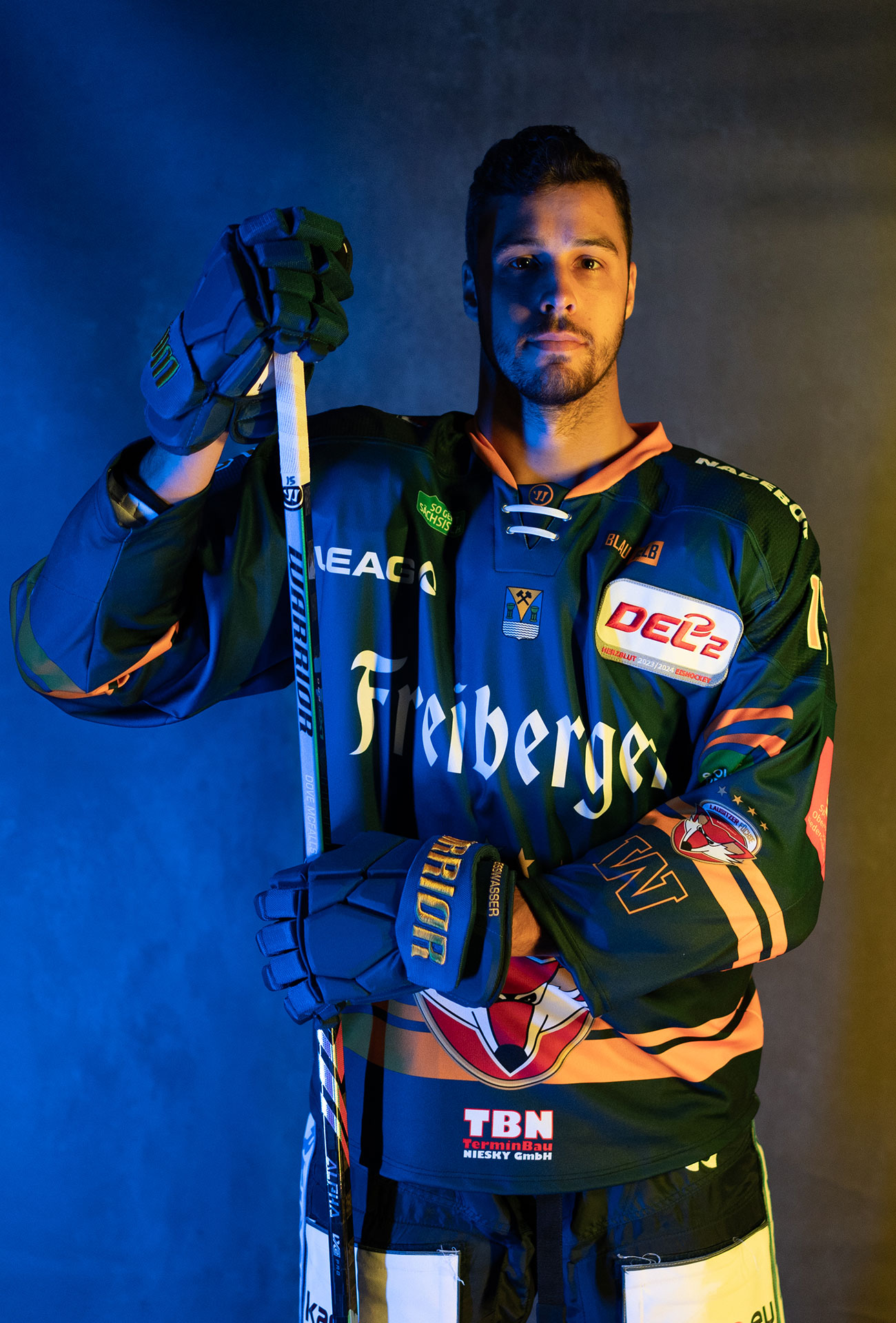 Sam Dove-McFalls in einer Pose mit Eishockeyausrüstung und Schläger