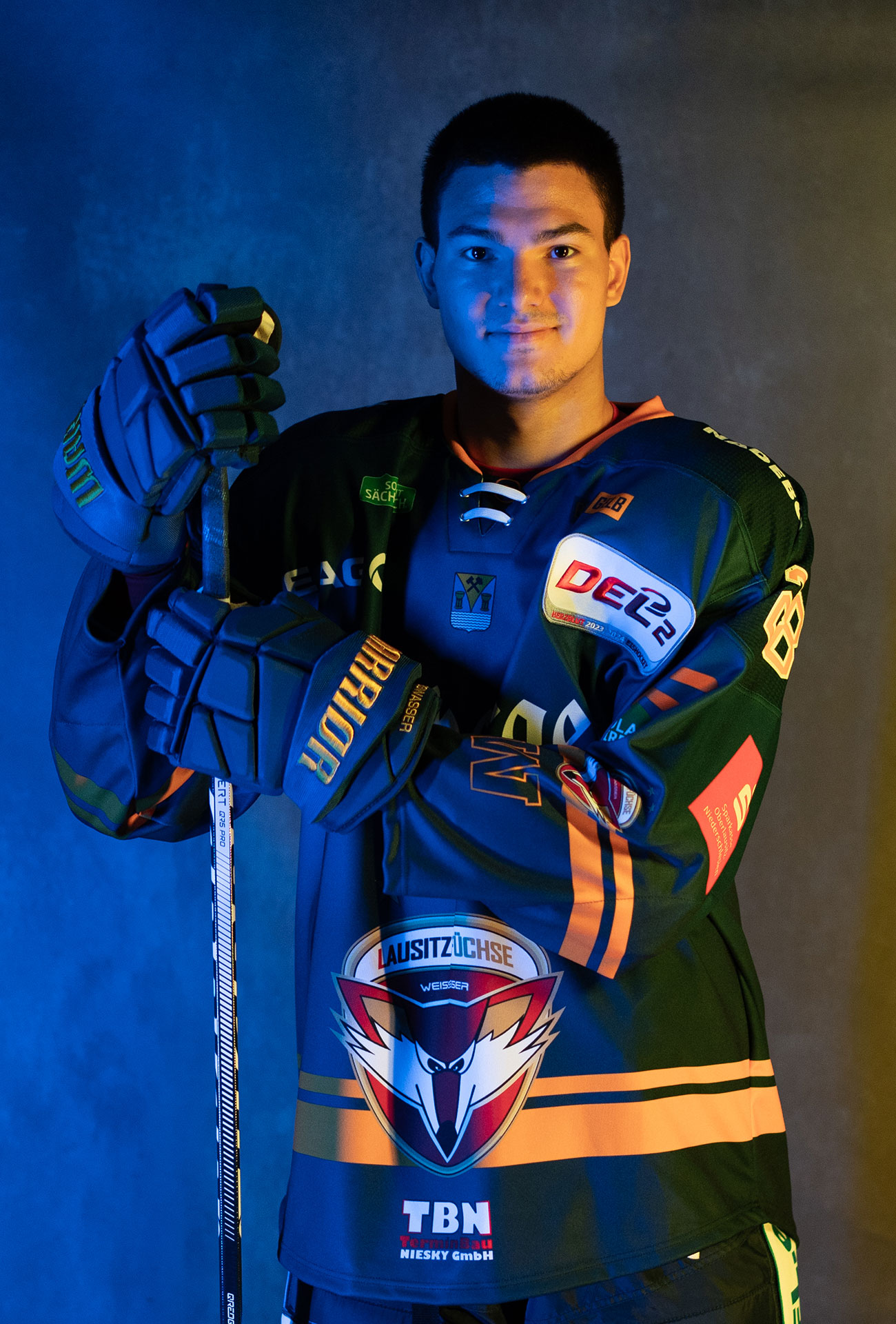 Justin van der Ven in einer Pose mit Eishockeyausrüstung und Schläger